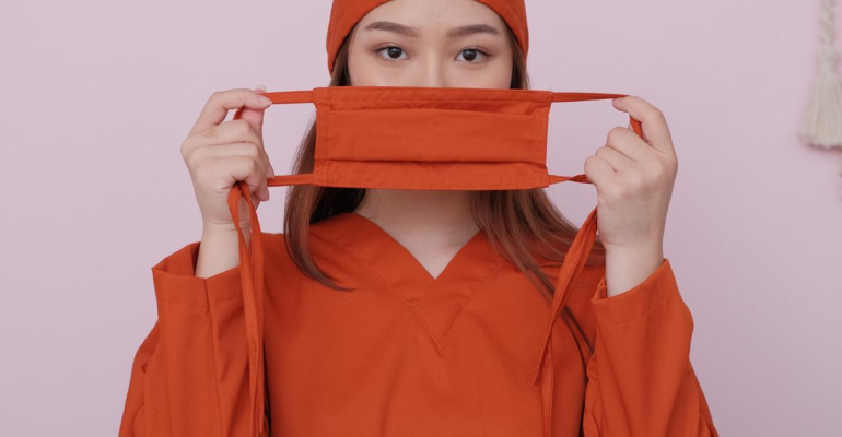 Detail scrub medis orange dengan masker dan penutup kepala tenaga kesehatan tampilan close up